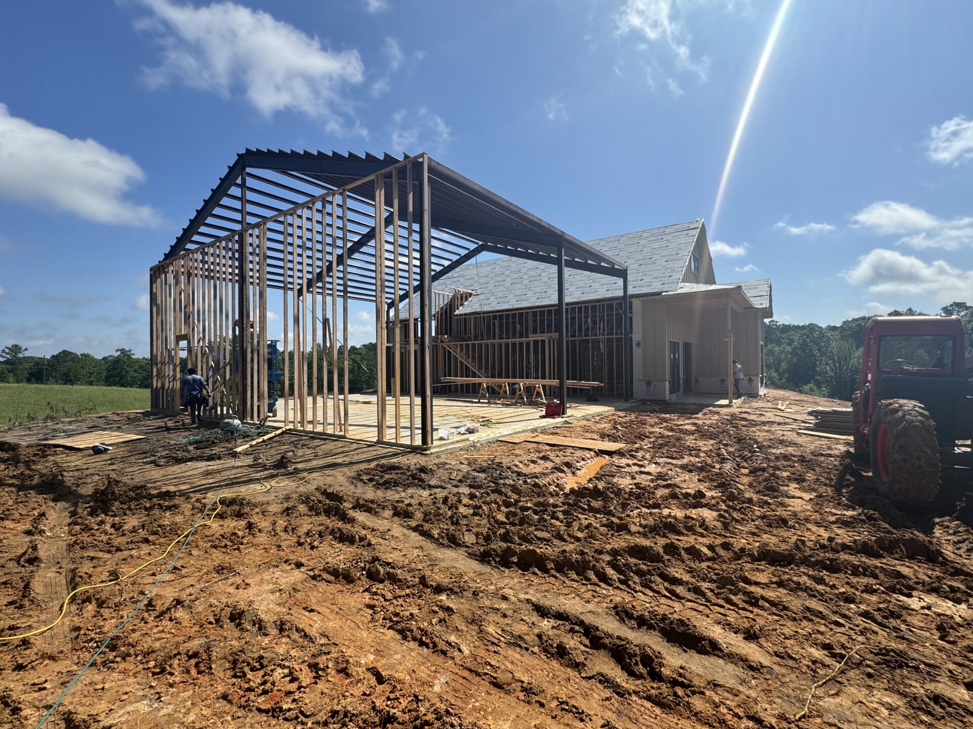 A barn under construction in a field, surrounded by open space and nature's beauty.