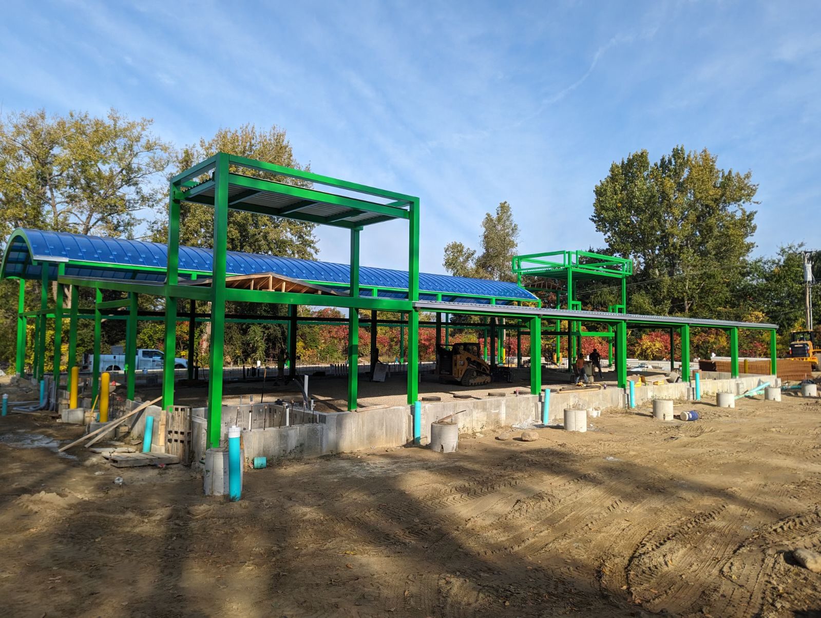 A green building under construction against a blue sky.