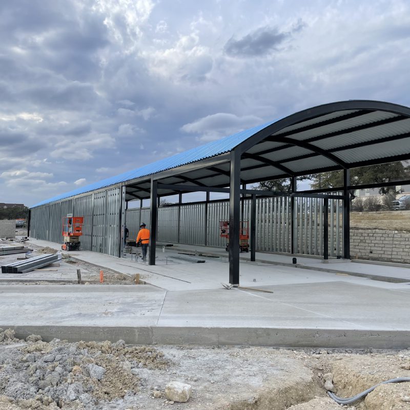 A carport under construction with a blue roof.