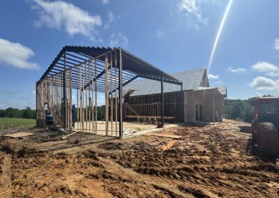 Rural scene of barn construction with a tractor in the background.