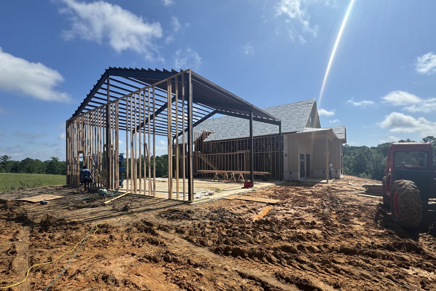 Rural scene of barn construction with a tractor in the background.